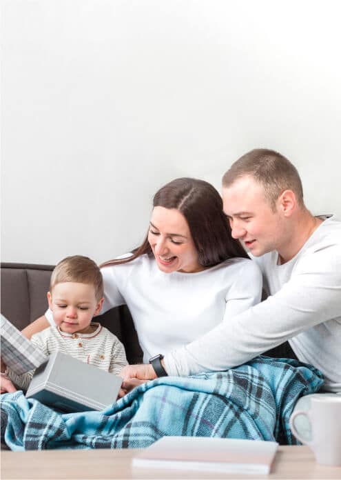 A family of four sitting on a couch, engrossed in a laptop together, enjoying quality time at home.